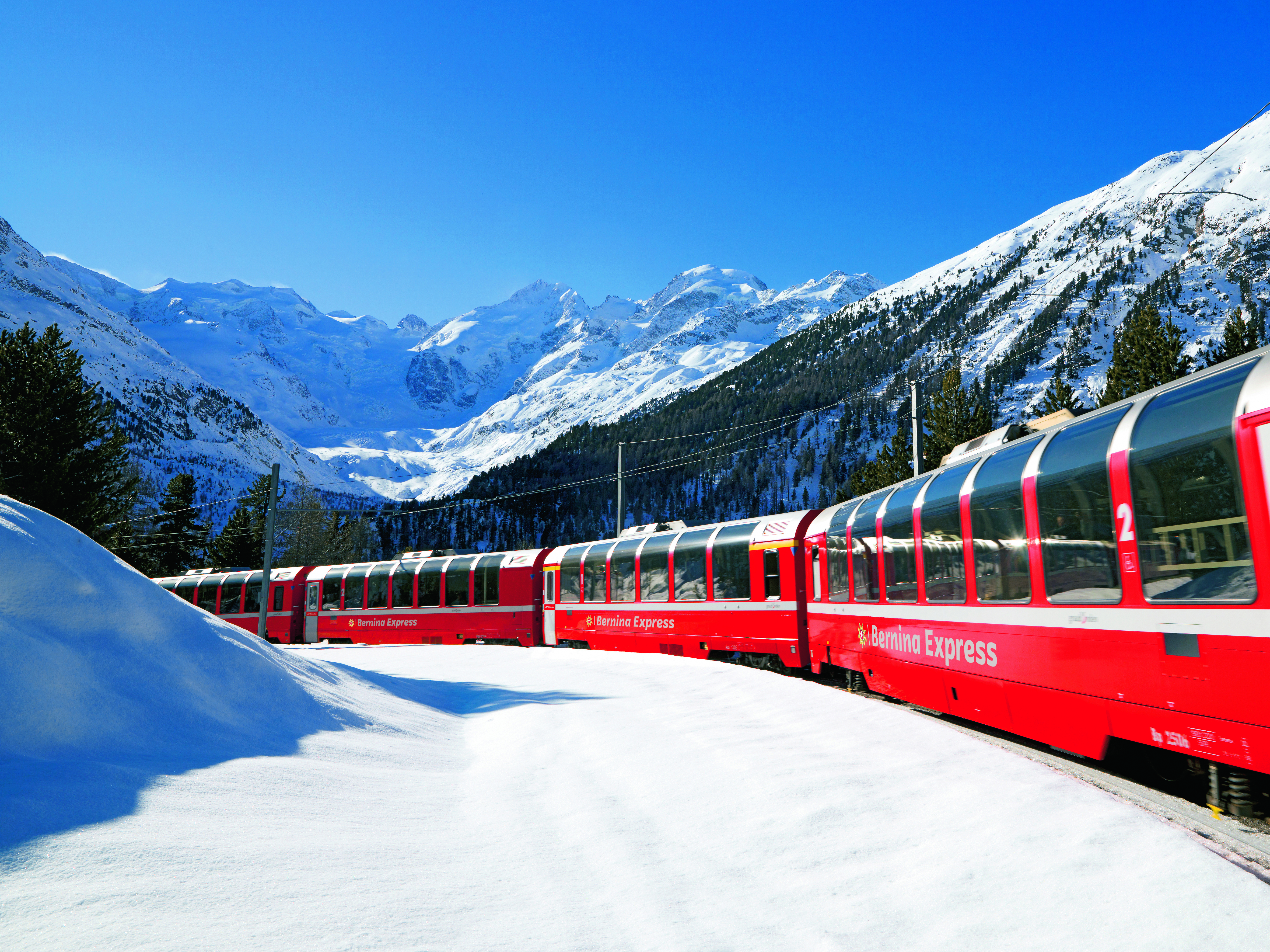 Der Berninaexpres mit schneereicher Landschaft und blauem Himmel
