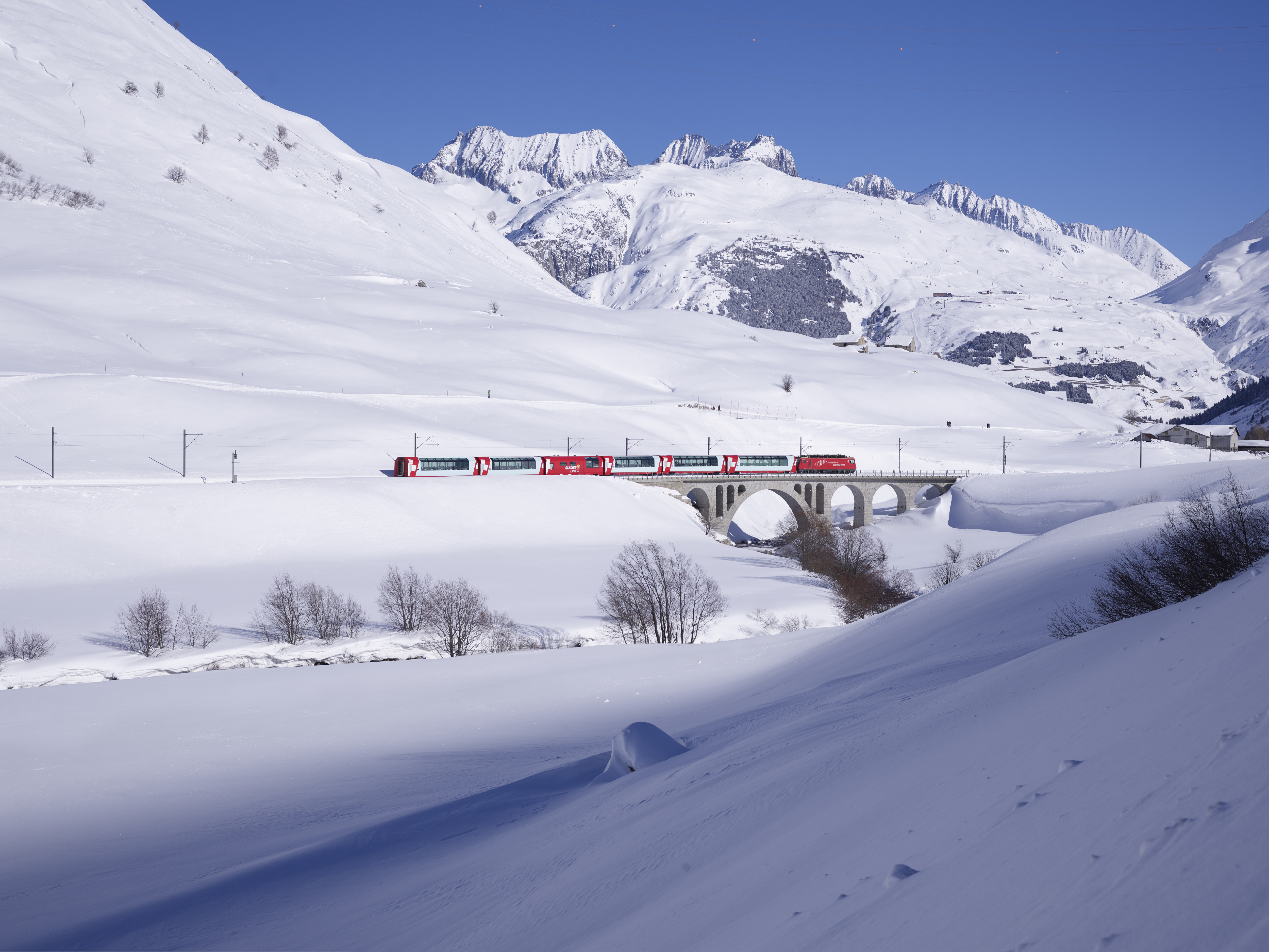 Der Berninaexpres mit schneereicher Landschaft und blauem Himmel