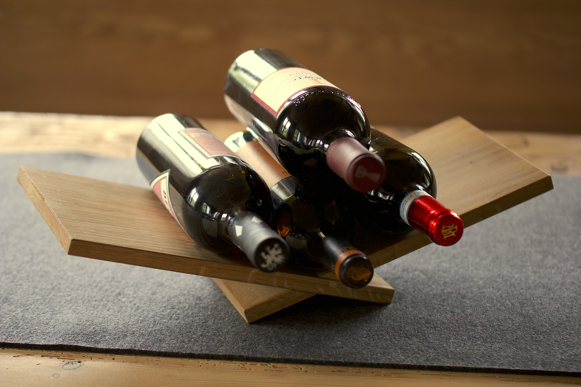 Weinliege Eine Weinliege aus Holz auf einem Tisch, darauf 4 Flaschen Wein